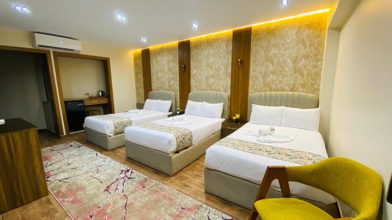 A hotel room with two single beds, a desk, a chair, and a large window.