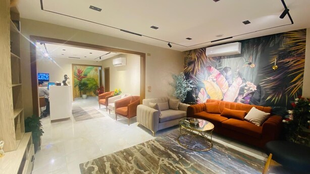 A modern hotel lobby with a reception desk, seating area with sofas and armchairs, and a large tropical mural on the wall. - Golden Season Hotel  (Cairo)