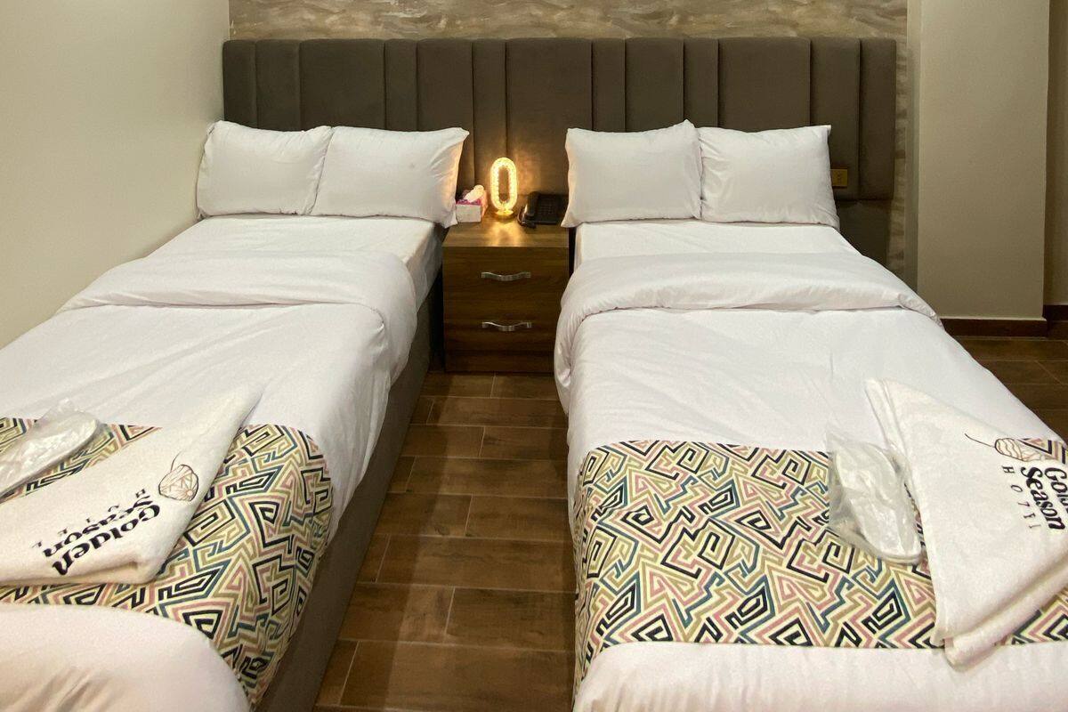A hotel room with two beds, a stone wall, and a modern design.
