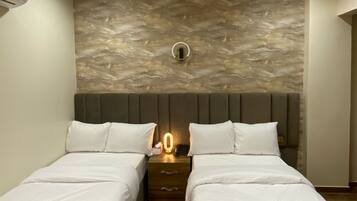 A hotel room with two beds, a stone wall, and a modern design.