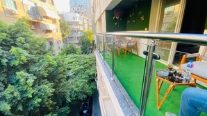 A balcony with a green artificial turf, a metal railing, and a table with chairs. - Golden Season Hotel  (Cairo)