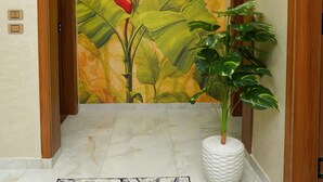 A hallway with a large floral mural, a potted plant, and marble flooring. - Golden Season Hotel  (Cairo)