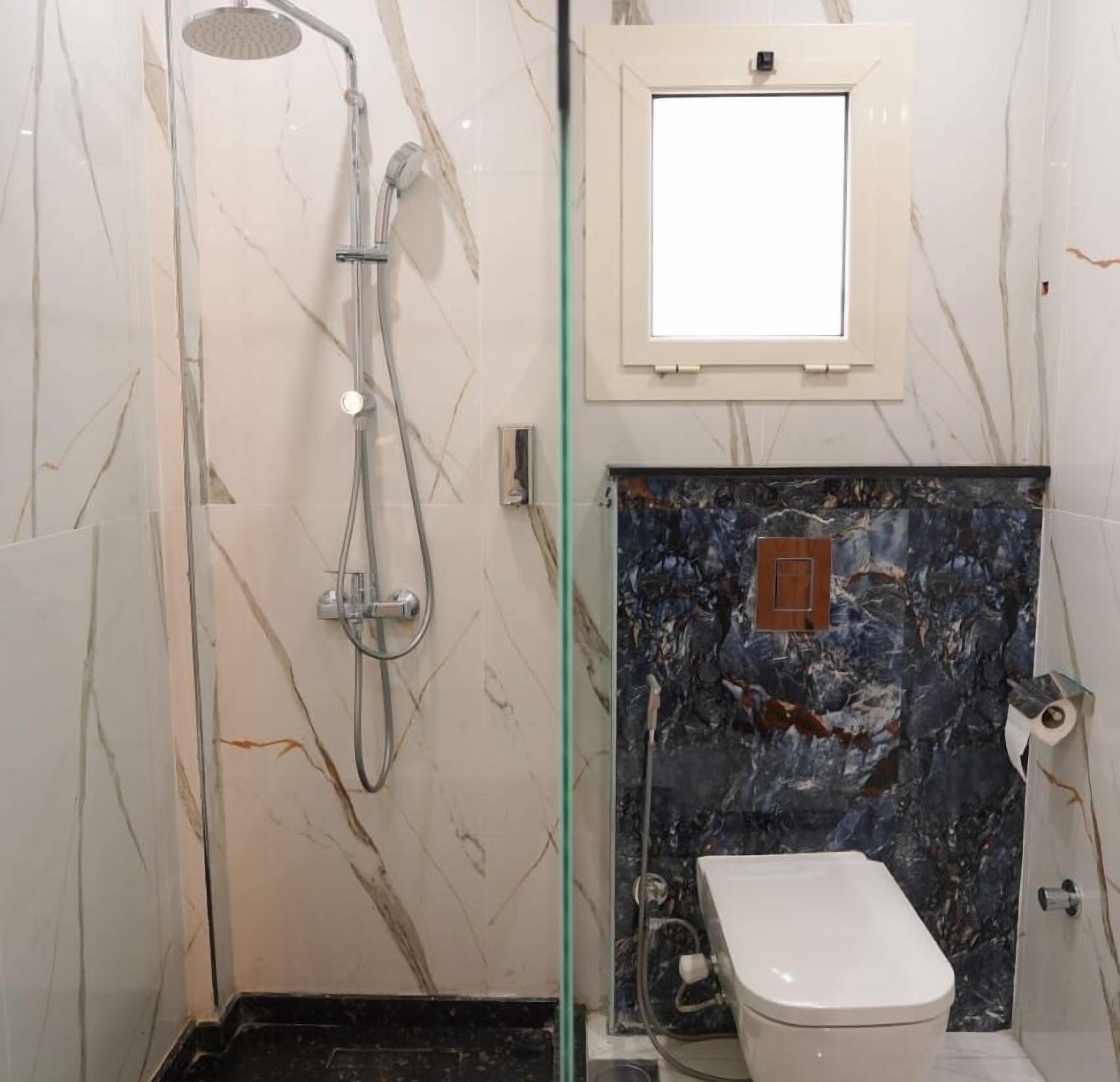 A bathroom with a shower, toilet, and a marble wall.