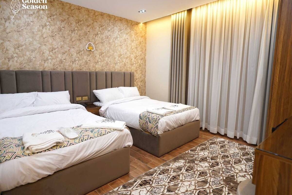 A hotel room with two beds, a patterned rug, and a marble wall.