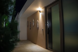 A hallway with a sliding glass door, a light fixture, and three surfboards mounted on the wall. - La Résidence Sea Plaza (Dakar)