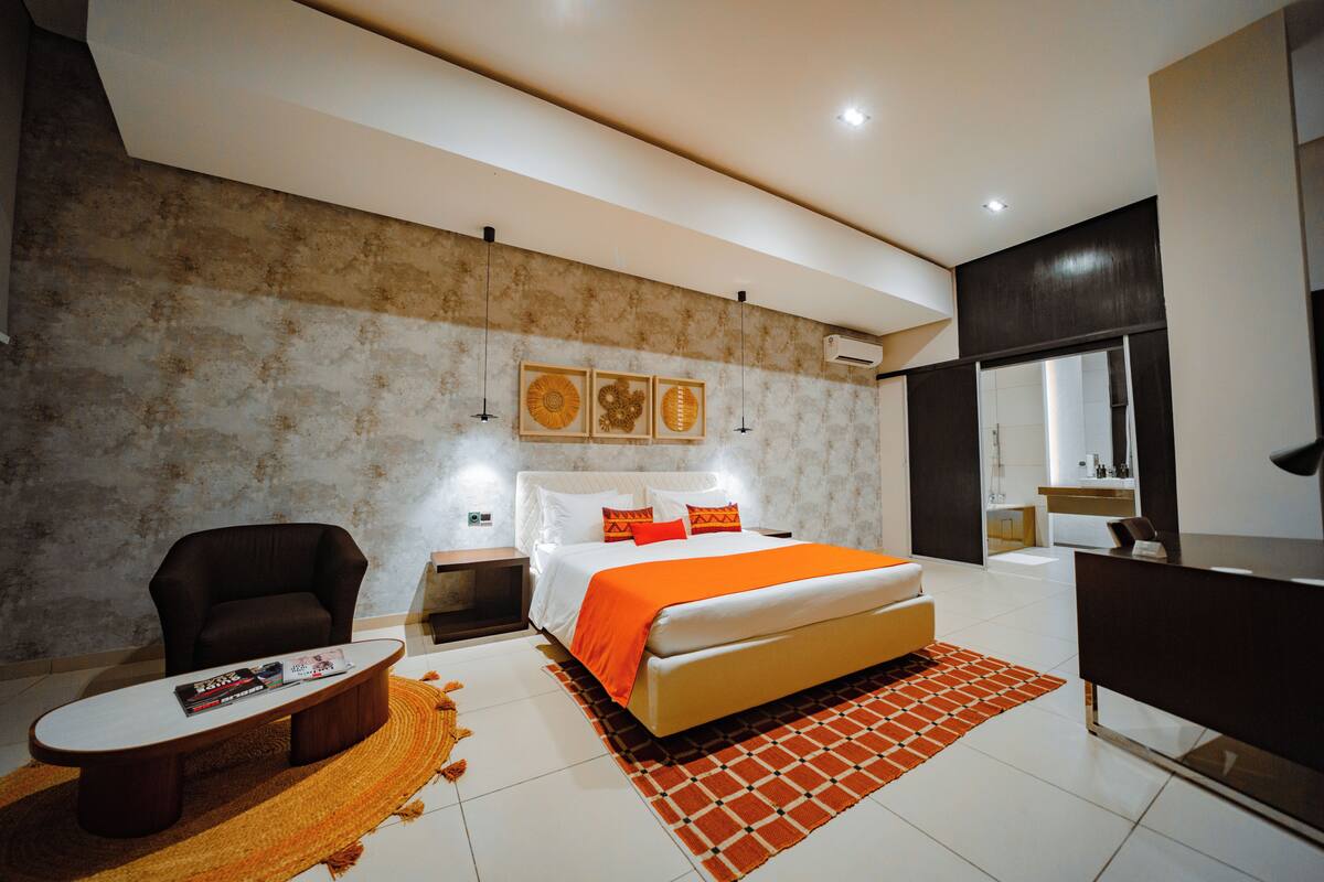 A modern bedroom with a bed, a chair, a coffee table, and a desk.