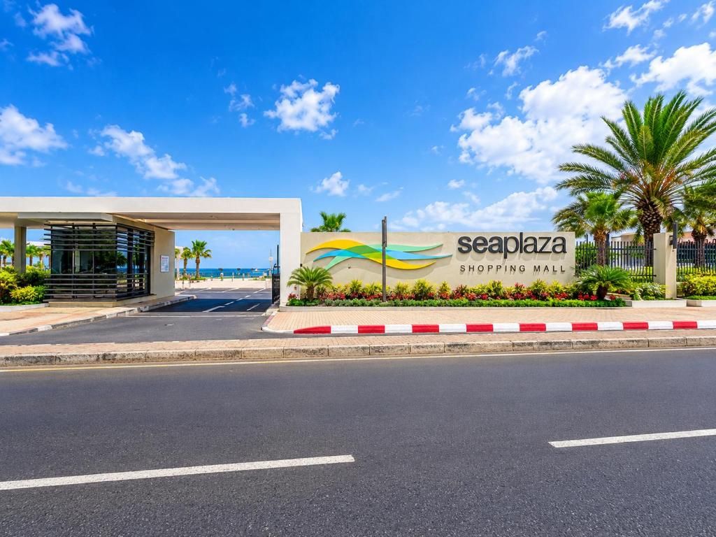 A shopping mall entrance with a sign reading 'seaplaza shopping mall' and a covered walkway.