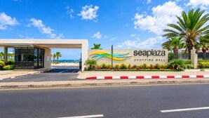 A shopping mall entrance with a sign reading 'seaplaza shopping mall' and a covered walkway. - La Résidence Sea Plaza (Dakar)