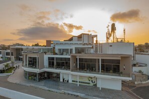 A modern building with multiple floors, large windows, and a rooftop with communication equipment. - La Résidence Sea Plaza (Dakar)