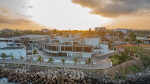 Un hotel costero de diseño moderno, con una estructura curva destacada, un litoral rocoso y vistas al mar.