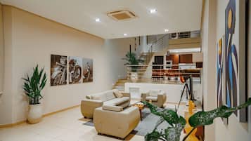 Una sala de estar moderna con un conjunto de sofás, una escalera que lleva a un nivel superior y obras de arte colgadas en la pared.