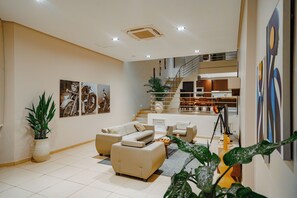 Un salon moderne comprenant un ensemble de canapés, un escalier menant à un niveau supérieur et des œuvres d’art accrochées au mur.