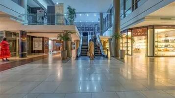 Un vaste espace intérieur doté d’un escalier central, de plantes en pot et d’un magasin appelé « TABOU » situé sur la droite.