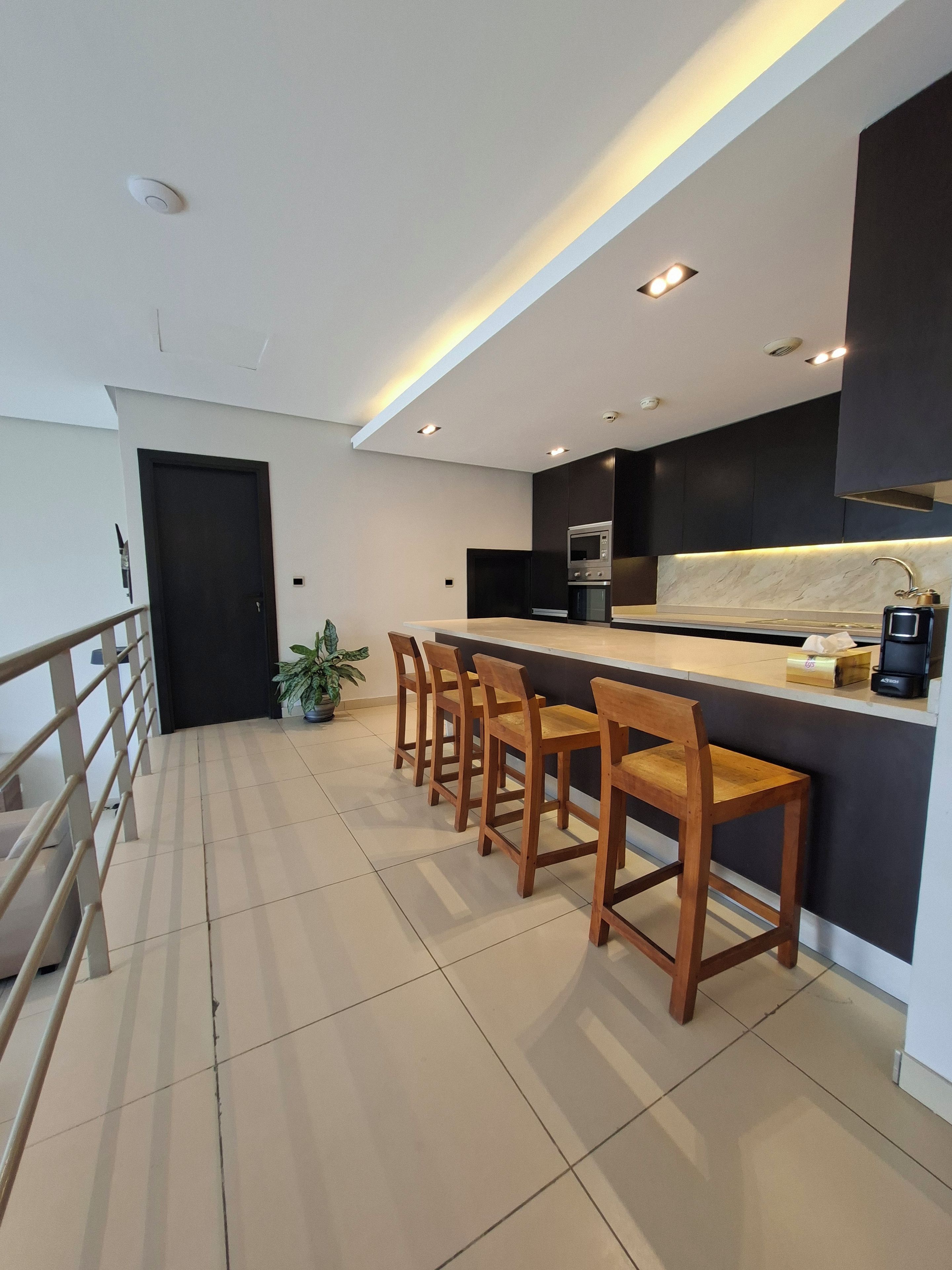 Cozinha moderna com área de bar, equipada com micro-ondas, forno e máquina de café.