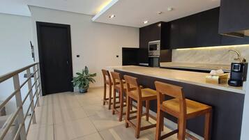 Cozinha moderna com área de bar, equipada com micro-ondas, forno e máquina de café.