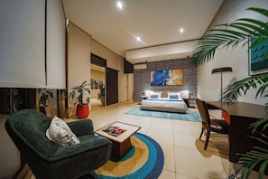 A modern bedroom with a large bed, a desk, and a green armchair. - La Résidence Sea Plaza (Dakar)