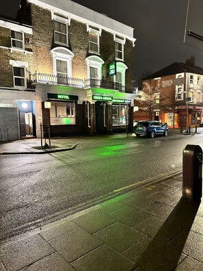 Et hotel med grøn skiltning, en restaurant med grøn skiltning, og en bil parkeret på gaden.
