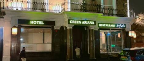 A hotel with a green sign labeled "GREEN ARIANA" and a restaurant sign.