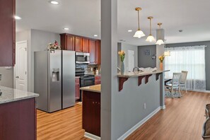 A modern kitchen with stainless steel appliances, wooden cabinets, and a dining area with a table and chairs.