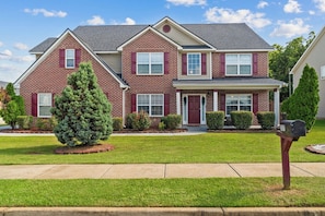 A two-story brick house with a front porch, a mailbox, and a well-maintained lawn.