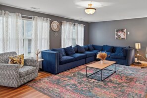 A living room with a sectional sofa, a patterned armchair, a coffee table, and a decorative vase.