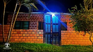 A brick building with a glass door entrance, surrounded by palm trees and greenery.