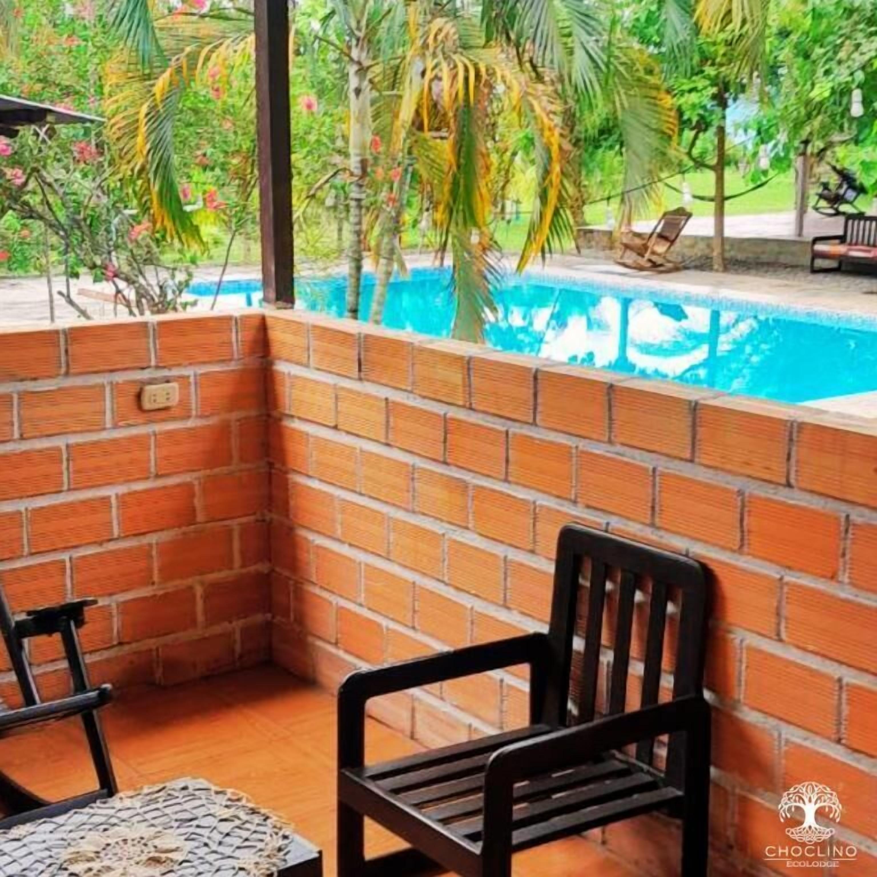 A corner of a room with a brick wall, a pool, and a chair.