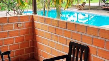 A corner of a room with a brick wall, a pool, and a chair.