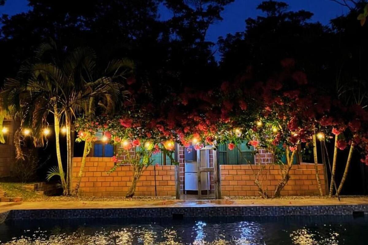 A nighttime view of a building with a brick wall, a small entrance, and a pool in the foreground.