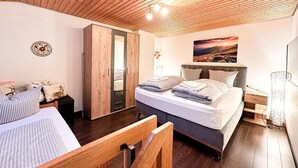 Ein Schlafzimmer mit Bett, Nachttischen, einem Kleiderschrank und einem Oberlicht.