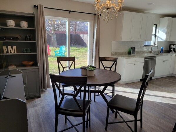 A modern kitchen with white cabinets, a dining table with chairs, and a chandelier. - Spacious 4BE/2BA house with big yard in Downtown Plano (Plano)