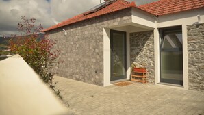 Un bâtiment moderne avec une façade en pierre, un toit recouvert de tuiles rouges et un chauffe-eau solaire.