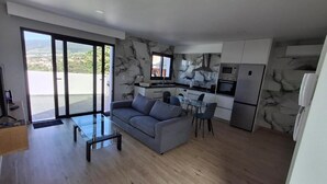 Un salon moderne avec un canapé, une table basse en verre et un coin repas avec des chaises.