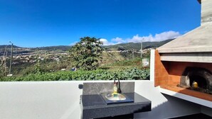 Une terrasse sur le toit avec un évier en pierre, un four encastré et une vue sur une ville lointaine.
