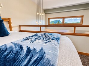 Un dormitorio con cama, cabecera de madera, ventana con vistas y lámpara colgante.