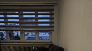 A room with a white table and chairs, a radiator, and a window with blinds.