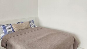 A bedroom with a bed, pillows, a clock, and a rug.