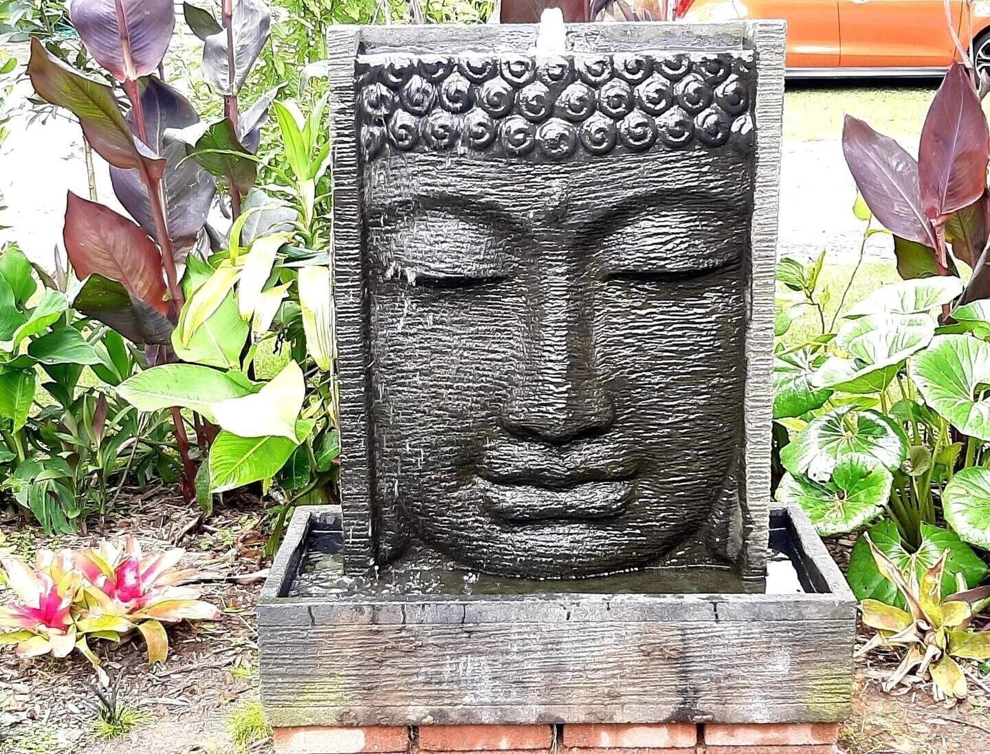 Estátua de Buda de pedra com um espelho d'água em um jardim.