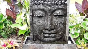 Estátua de Buda de pedra com um espelho d'água em um jardim.