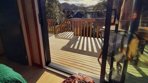 Udsigt fra et værelse med en skydedør til en udendørs terrasse med gelænder og en klar himmel.