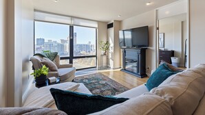Ein modernes Wohnzimmer mit großem Fenster, Flachbildfernseher, einer Couch und einem Couchtisch.