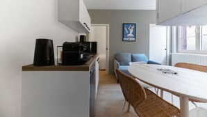 Una cocina moderna con estufa integrada, cafetera y comedor con mesa blanca y sillas de mimbre.