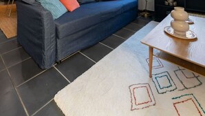 A modern living room with a dark blue sofa, a white rug with geometric patterns, and a wooden coffee table. - Le Charlot - 27 rue charlot - Vichy (Vichy)
