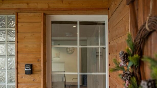 A wooden door with a glass panel, a doorknob, and a small black device on the wall. - Le Charlot - 27 rue charlot - Vichy (Vichy)