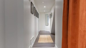A hallway with a wooden floor, white walls, and a series of framed pictures on the left wall. - Le Charlot - 27 rue charlot - Vichy (Vichy)