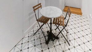 A compact kitchen with a white countertop, a sink, and a microwave. There is a small dining area with a round table and wooden chairs. - Le Paradis - 4 rue du Paradis - Clermont (Clermont-Ferrand)