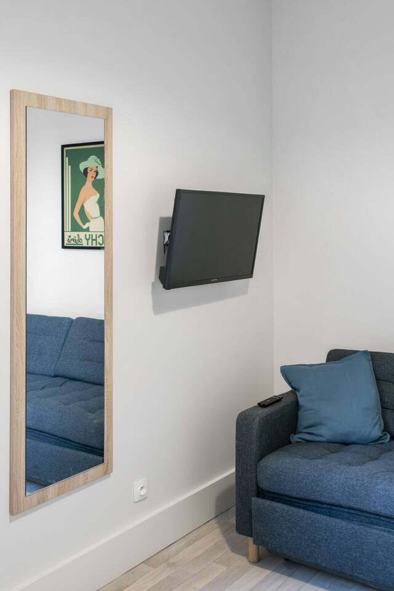 A room with a large mirror, a mounted TV, and two sofas.