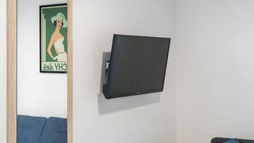 A room with a large mirror, a mounted TV, and two sofas.