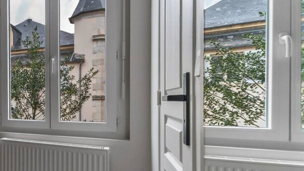 A room with a large window, a radiator, and a door.