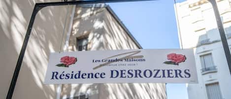 A sign for 'Résidence DESROZIERS' with a welcome message and a rose illustration.